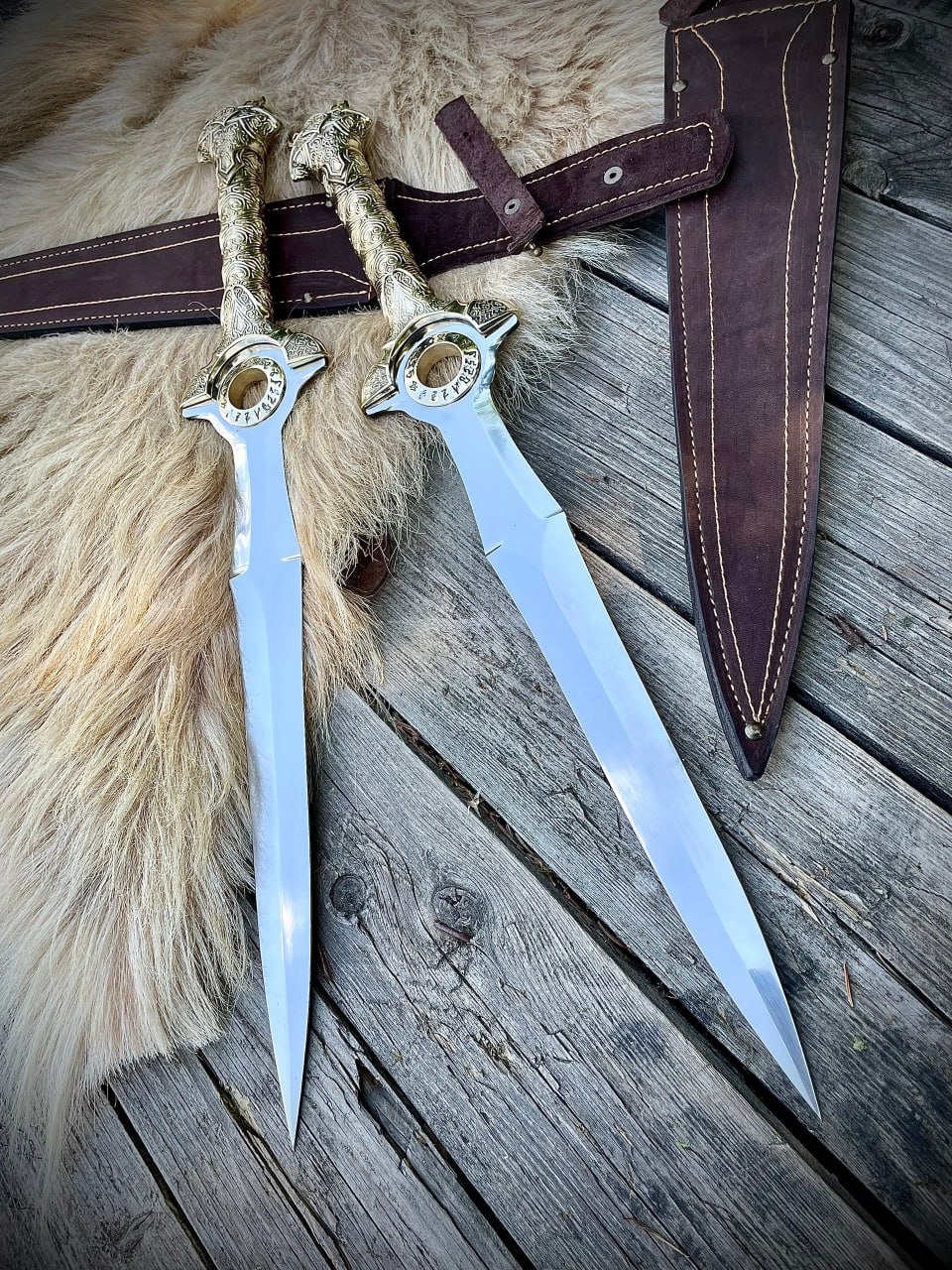 Пара изящных фэнтезийных кинжалов из Warcraft с блестящими клинками и кожаными прошитыми ножнами поверх меховой подстилки.