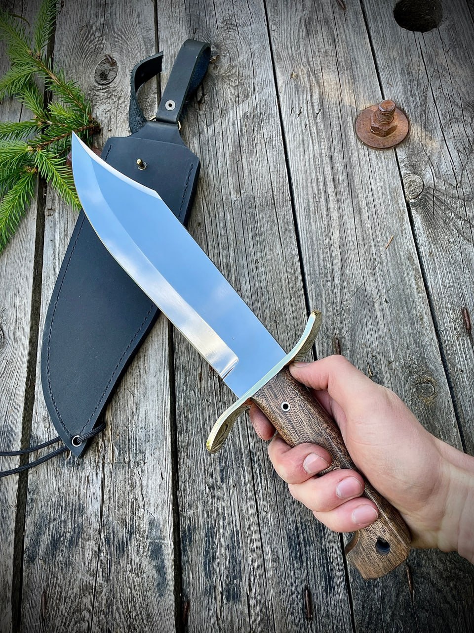 Кованый нож Wild West Bowie в руке, демонстрирующий размер и форму рукояти.