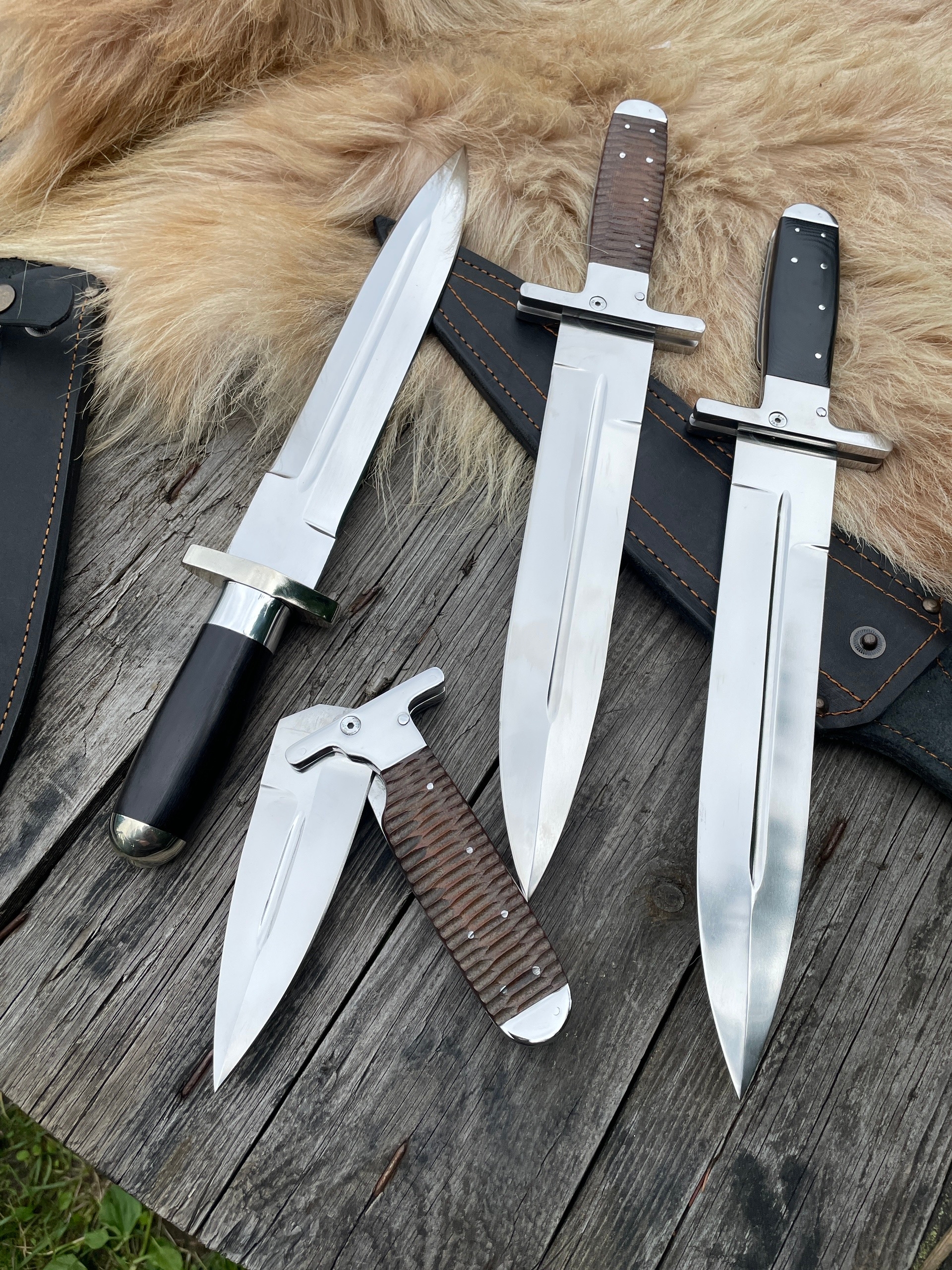 Нескладной кинжал Самсонова с чёрной рукоятью, разложенный «Егерь» с коричневой рукоятью «битый камень», сложенный «Егерь» с коричневой рукоятью и кинжал с чёрной рукоятью G10 в кожаных ножнах на клипсе